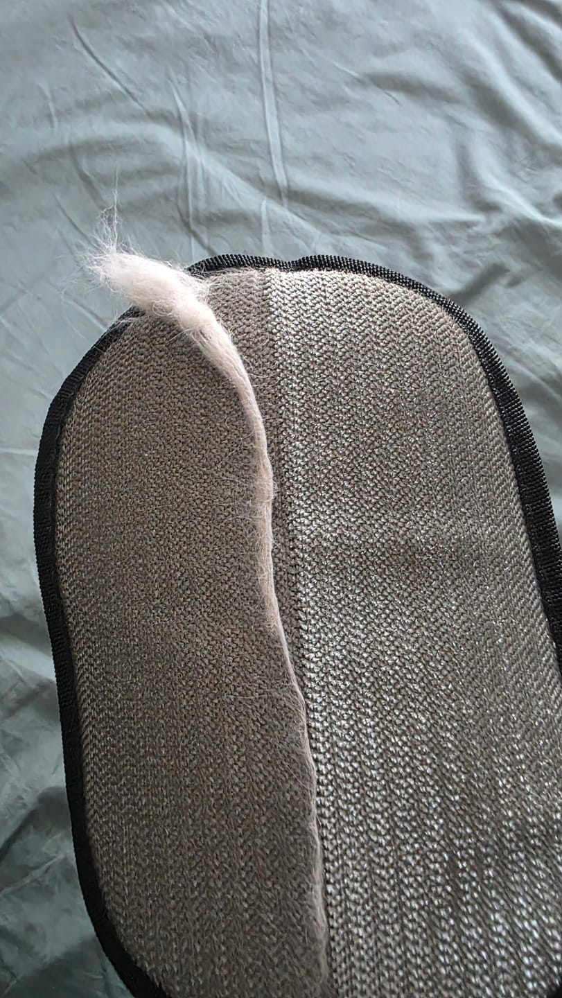Un mechón de pelo blanco levantado de la tela sobre la superficie del guante
